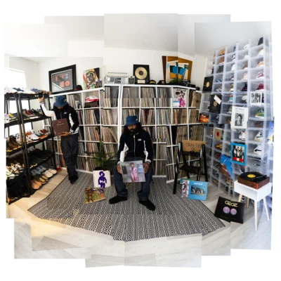 Dam-Funk standing in his Los Angeles record room surrounded by vinyl, photographed by Eilon Paz for Dust & Grooves.