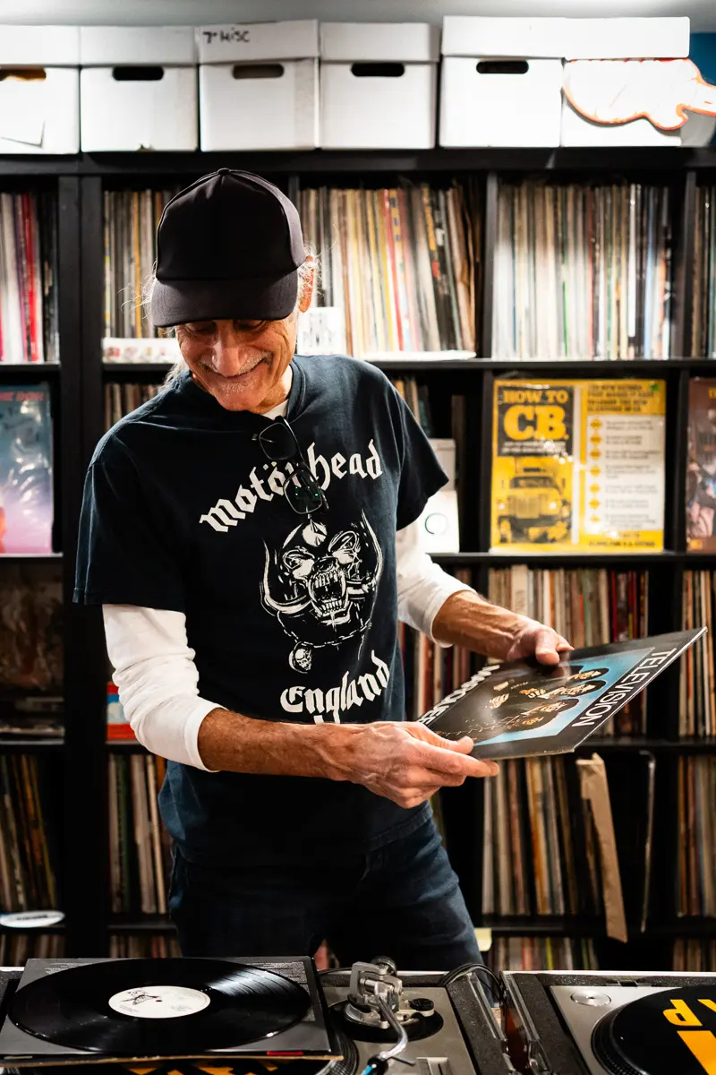 KEXP music director Kevin Cole in his home record basement in Seattle, pictured with shelves of vinyl and personal music memorabilia for Dust & Grooves Volume 2.