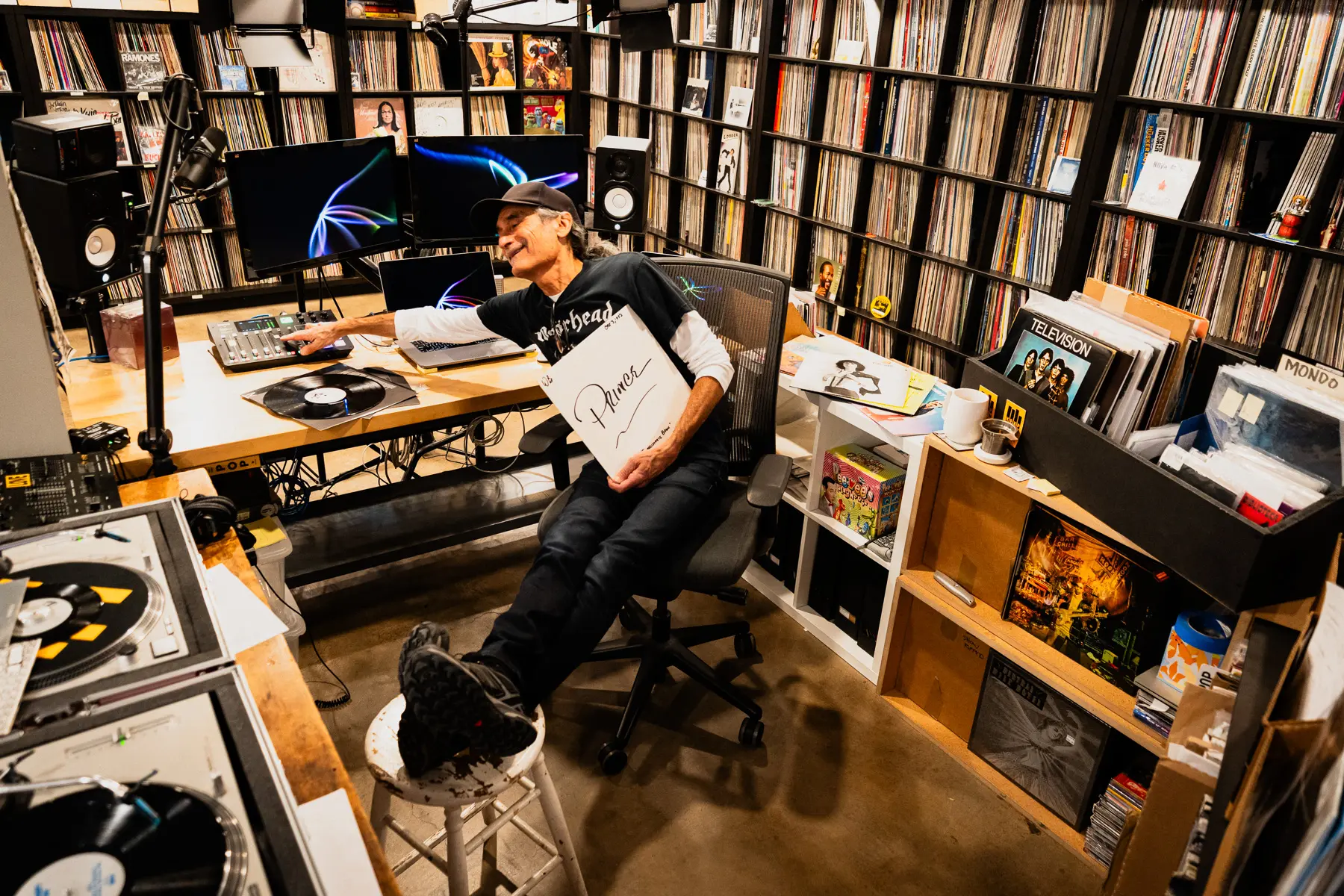 KEXP music director Kevin Cole in his home record basement in Seattle, pictured with shelves of vinyl and personal music memorabilia for Dust & Grooves Volume 2.